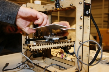 A pair of hands replacing the build platform on a 3D printer